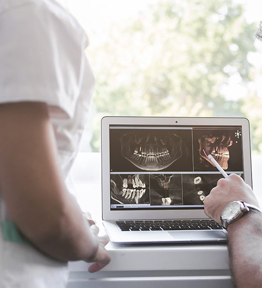 Dentist and team member examining all digital dental x-rays on computer screen