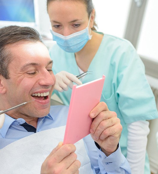 a patient checking their dental bridge with a mirror