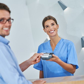 Smiling man making payment at dental office front desk