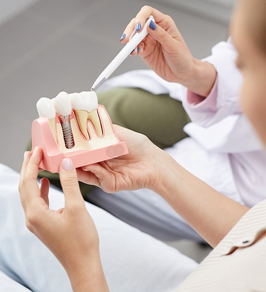 Dentist and patient looking at dental implant supported replacement tooth model