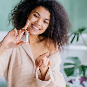 Smiling woman preparing to floss her teeth