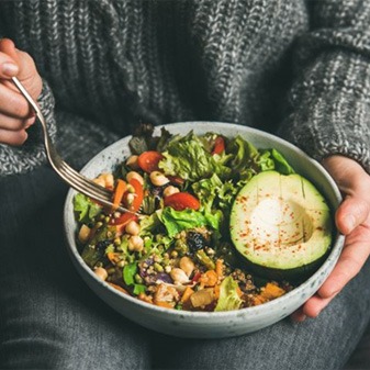 Woman’s hands holding colorful bowl of salad