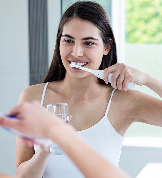 Woman brushing teeth to prevent dental emergencies