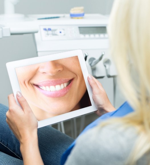 Woman looking at virtual smile design on tablet computer