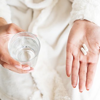 woman holding pills and water 