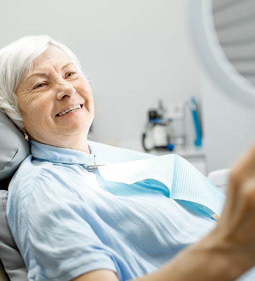 Woman looking at her smile after same day dentures treatment
