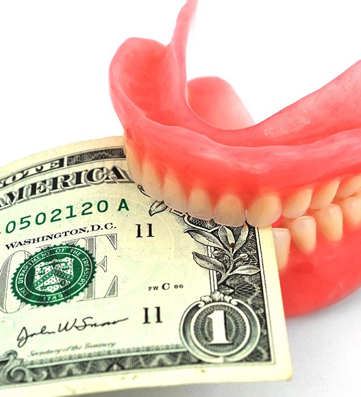A pair of dentures biting a dollar bill