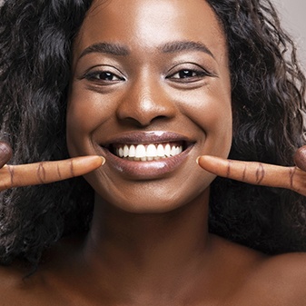 Patient pointing at her teeth, happy she could afford veneers