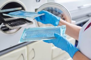 dental professional carefully placing packaged instruments into autoclave