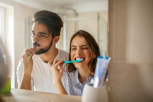 Young couple brushing their teeth in front of mirror